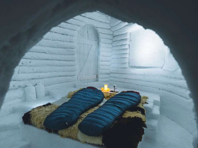 Zwei Schlafsäcke liegen auf einem Bett in einem schneebedeckten Raum