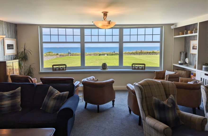 Ein Wohnzimmer mit vielen Möbeln und einem großen Fenster mit Blick auf das Meer