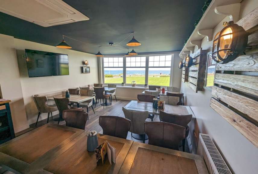 Ein Restaurant mit vielen Tischen und Stühlen und einem Fernseher