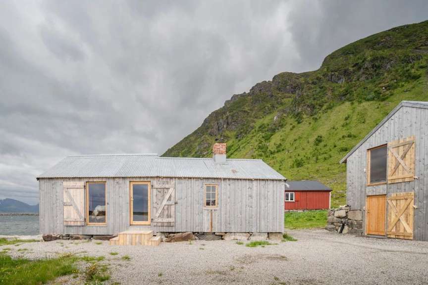 Ein kleines Holzhaus mit einem Metalldach steht neben einem roten Haus