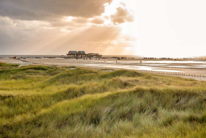 Die Sonne scheint durch die Wolken über einem Strand