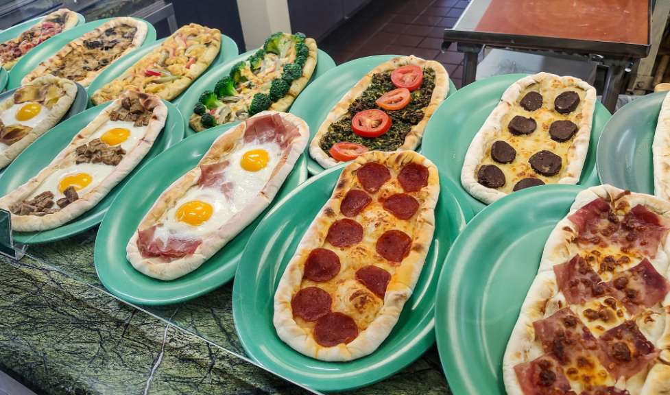 Verschiedene Pizzen stehen auf grünen Tellern auf einem Tisch