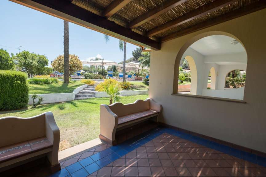 Eine Bank auf einer Veranda mit Blick auf einen Garten