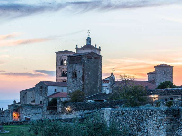 Ein kleines Dorf mit einer Kirche und einem Turm bei Sonnenuntergang