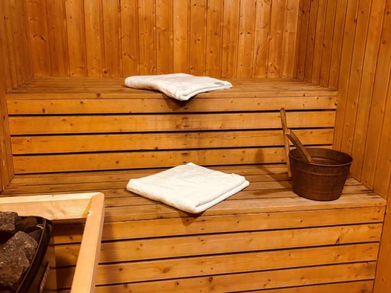 Eine Holzsauna mit zwei Handtüchern und einem Eimer