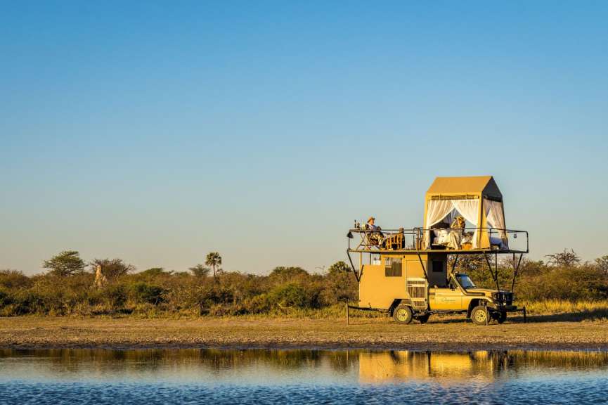 Ein Auto mit einem Zelt auf dem Dach sitzt neben einem Teich