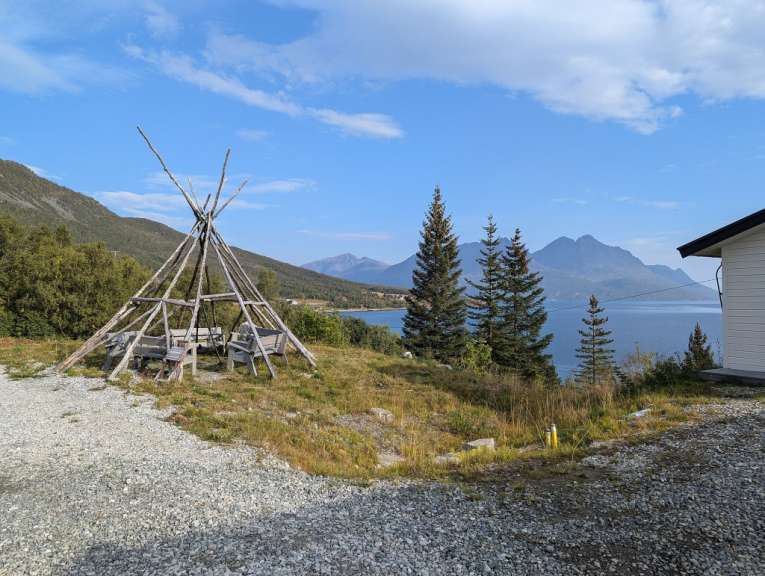 Ein teepee steht auf einem grasbewachsenen Hügel mit Blick auf einen See