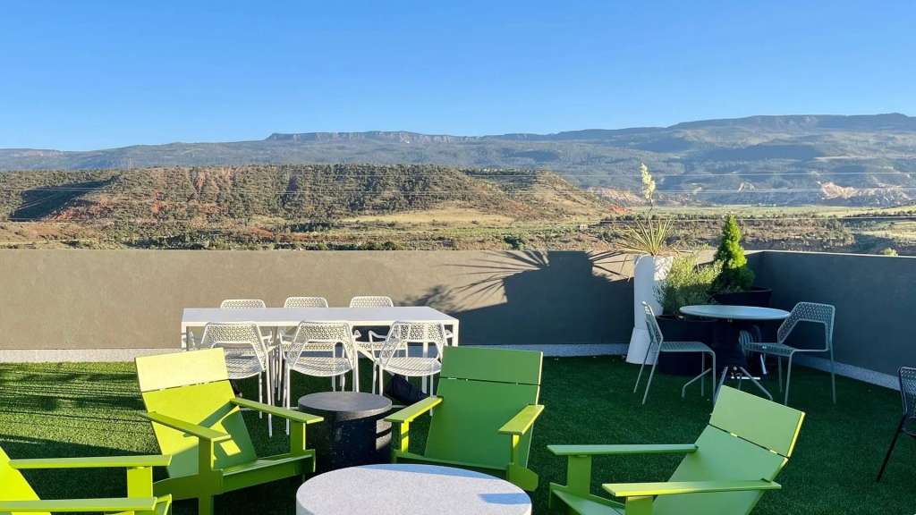 Eine Außenlounge mit Blick auf eine hügelige Landschaft unter einem klaren blauen Himmel.