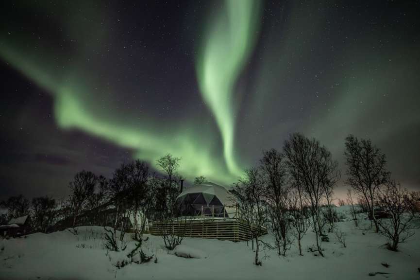 Das Nordlicht scheint über einem schneebedeckten Haus