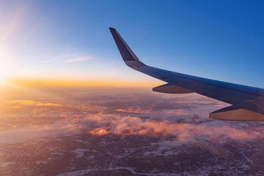 Ein Flugzeug fliegt bei Sonnenuntergang über den Wolken
