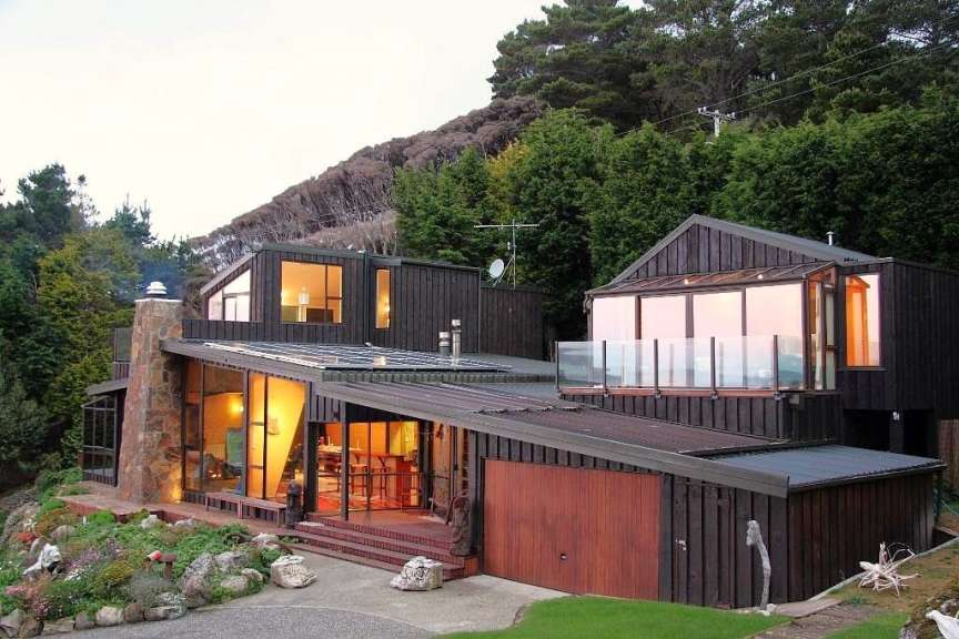 Ein schwarzes Haus mit vielen Fenstern und einer Garage