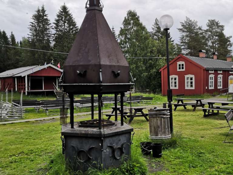 Ein kleines rotes Gebäude mit weißen Fenstern befindet sich hinter einem Grill