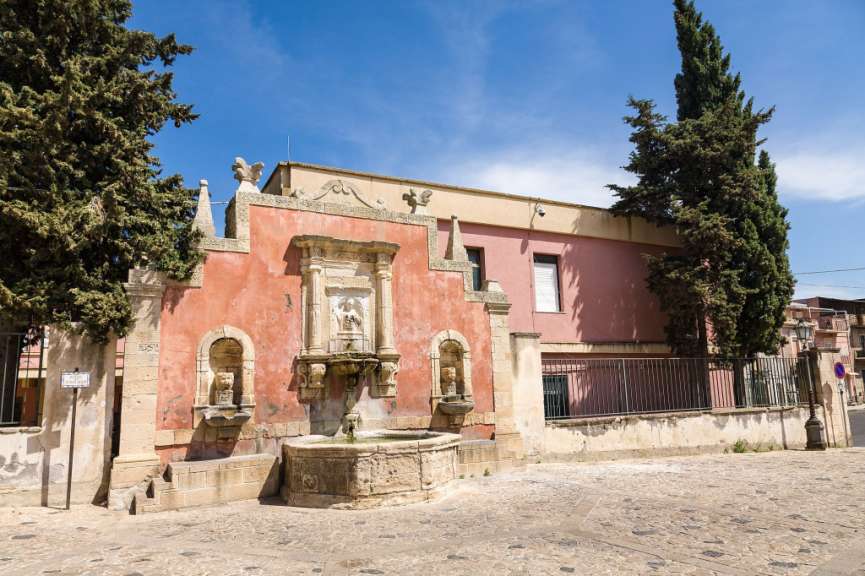 Ein rosa Gebäude mit einem Brunnen davor