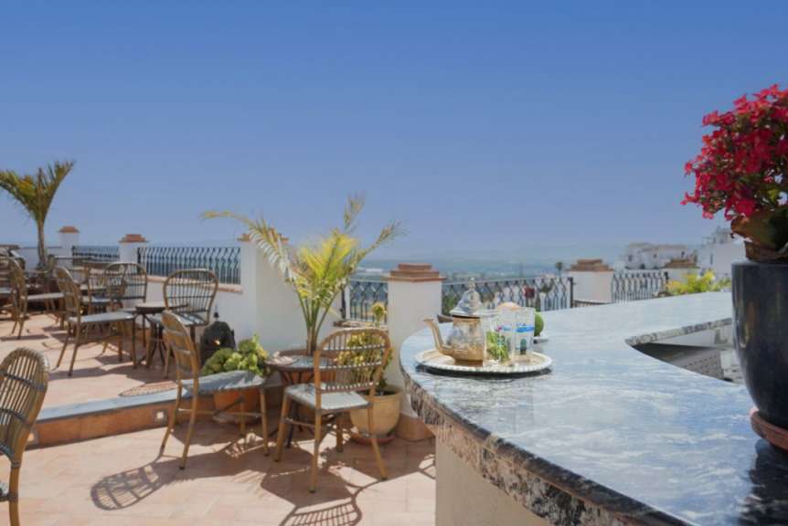 Eine Terrasse mit Tisch und Stühlen und einer Teekanne auf einem Tisch