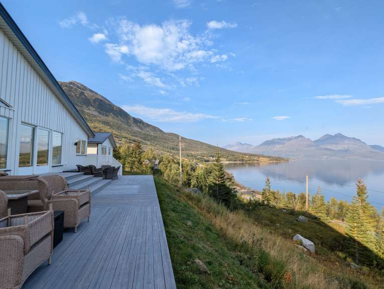 Ein weißes Haus mit einem Holzdeck mit Blick auf einen See