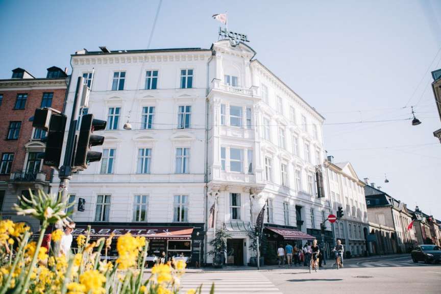 Eine Gruppe von Menschen steht vor einem weißen Hotel