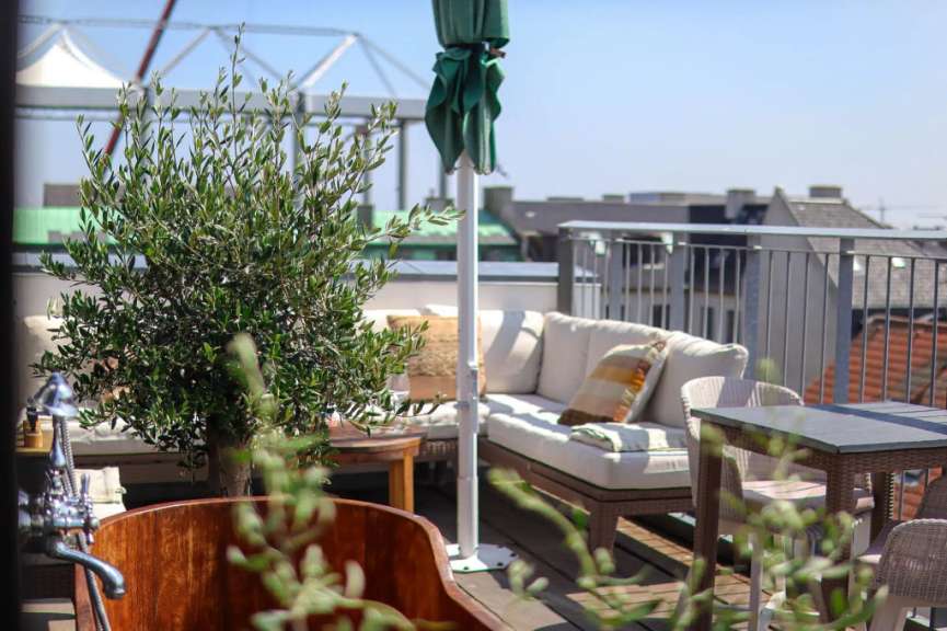Ein Balkon mit einer Couch und einem Tisch und einem grünen Regenschirm