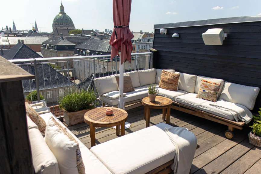 Ein Wohnzimmer auf einem Dach mit einem roten Regenschirm