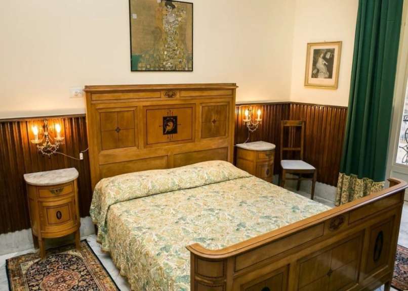 Ein Schlafzimmer mit einem Holzbett, zwei Nachttischen und einem Bild von Gustav Klimts "Der Kuss" an der Wand.