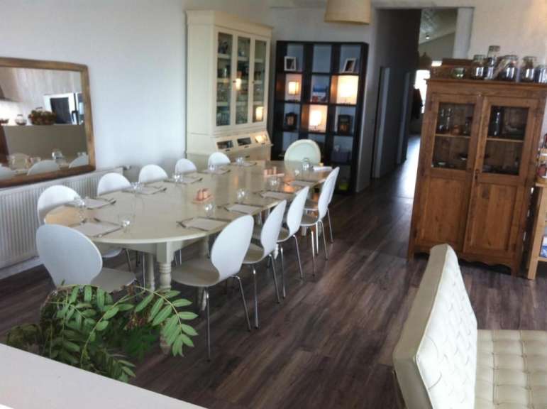 Ein Esszimmer mit einem langen Tisch und weißen Stühlen