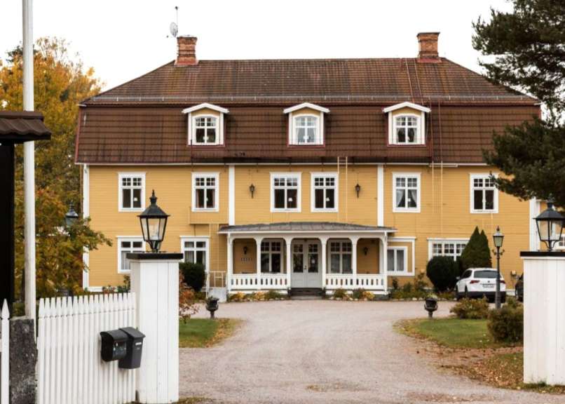 Ein großes gelbes Haus mit einem weißen Zaun davor