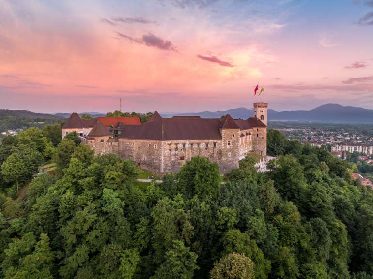 Ein großes Schloss auf einem Hügel mit Bäumen umgeben