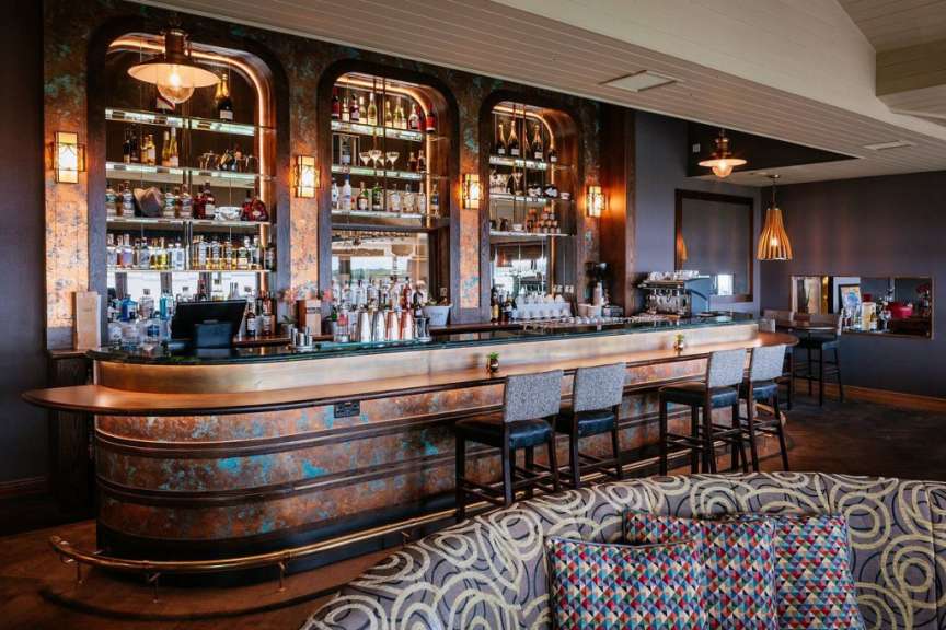 Eine lange Bar in einem Restaurant mit vielen Gläsern und Stühlen