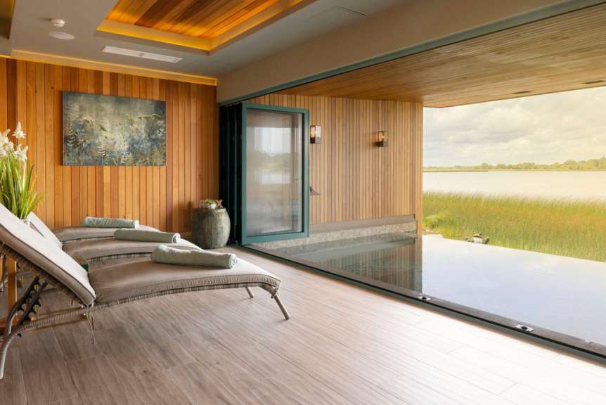 Ein Zimmer mit Liegestühlen und einem großen Fenster mit Blick auf einen See