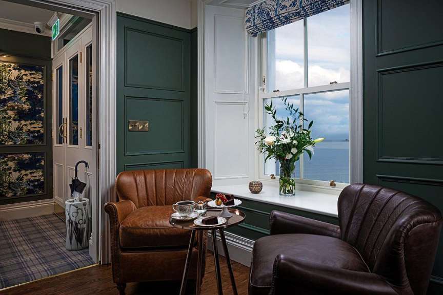 Ein Stuhl mit einer Tasse Kaffee auf einem Tisch neben einem Fenster