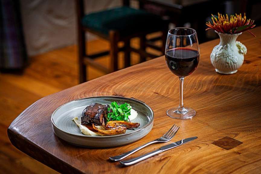 Ein Teller mit Essen und ein Glas Wein auf einem Holztisch