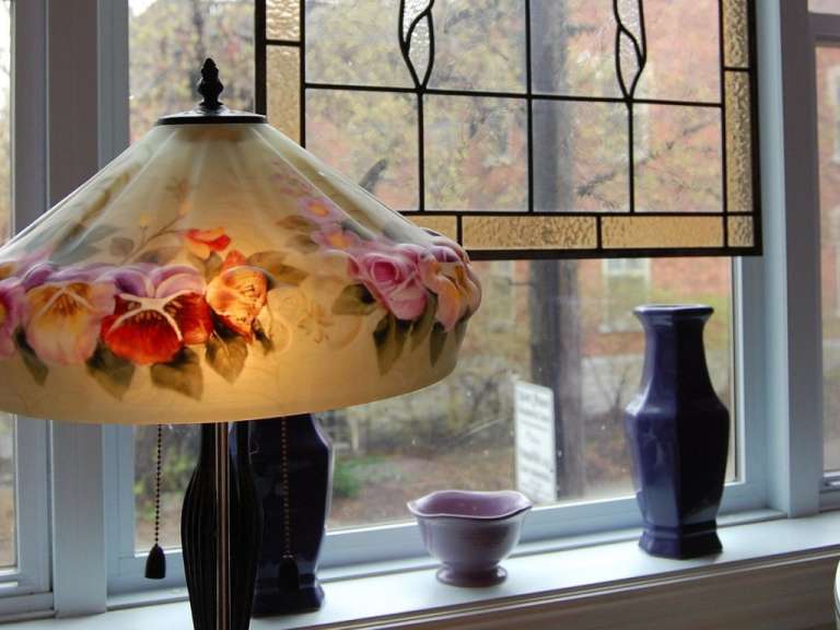Eine Lampe mit einem Blumenschirm steht vor einem Fenster