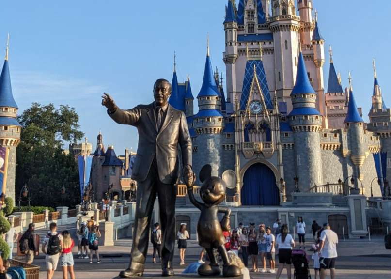 Eine Statue von walt disney und mickey mouse vor einem Schloss