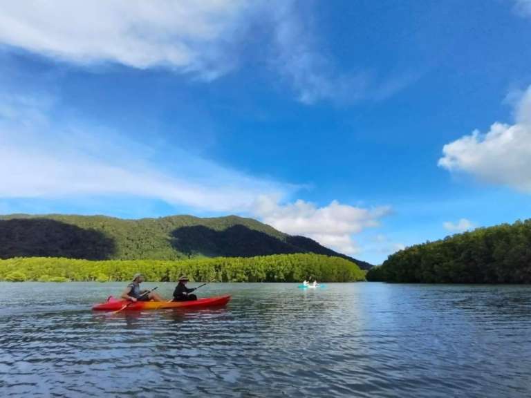 Zwei Menschen paddeln in einem Fluss mit Bergen im Hintergrund