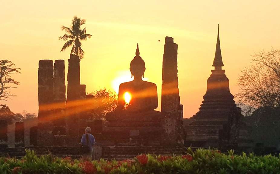 Die Sonne geht hinter einer buddhistischen Statue unter