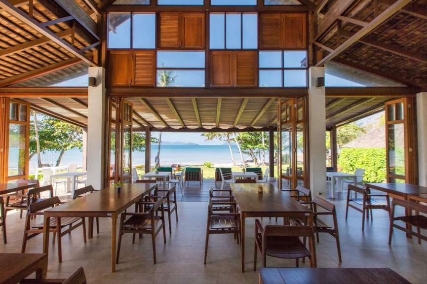 Ein Restaurant mit Holztischen und Stühlen mit Blick auf das Meer