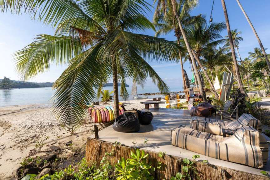Ein Strand mit bunten Stühlen und Kissen und Palmen