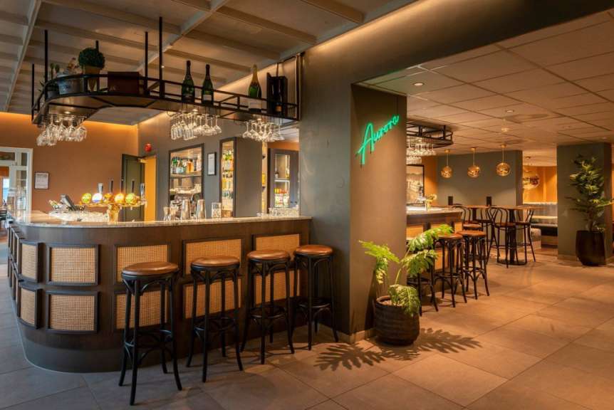 Ein Restaurant mit einer Bar und Stühlen und einem neongrünen Schild, das auf der Wand steht