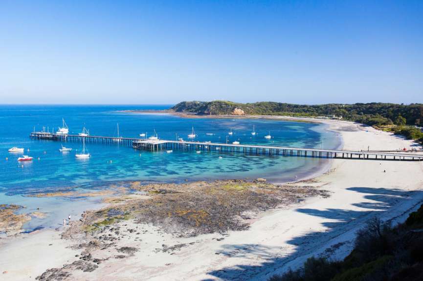 Ein Strand mit einem Pier und vielen Booten im Wasser