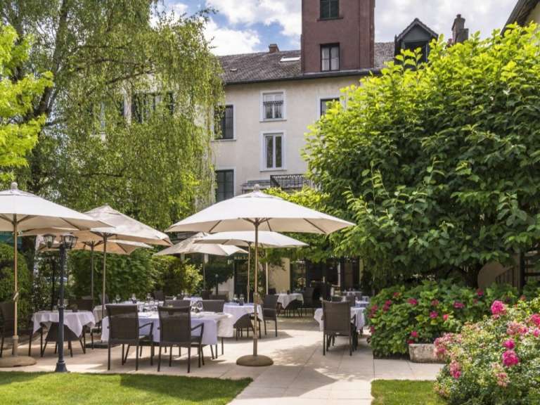 Eine Terrasse mit Tischen und Stühlen und Regenschirmen vor einem Gebäude
