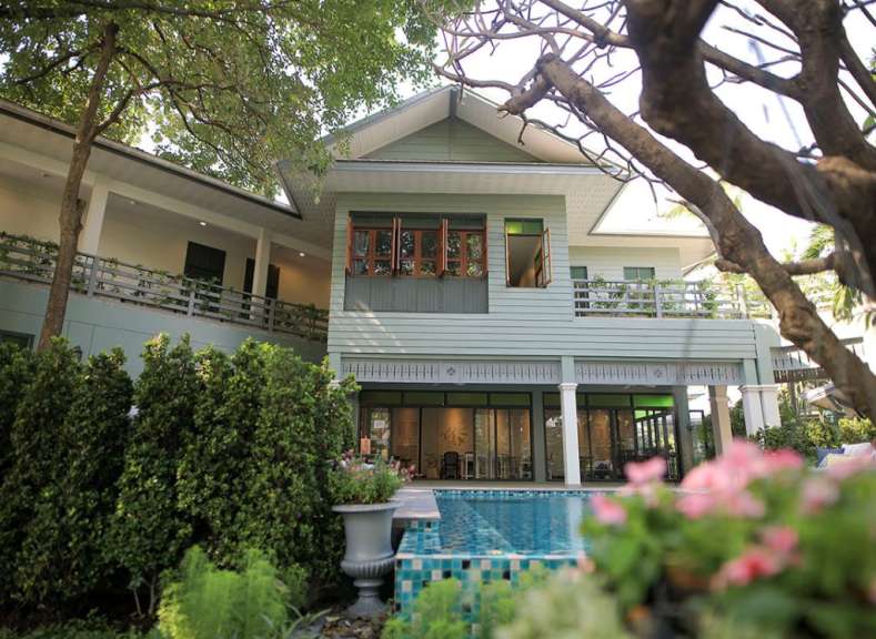 Ein grünes Haus mit einem Pool davor