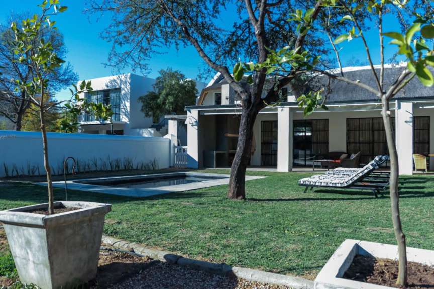 Ein Haus mit einem Pool und Liegestühlen im Garten