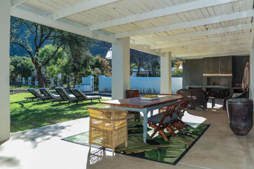 Eine Terrasse mit Tisch und Stühlen und einem Teppich mit Palmblättern darauf