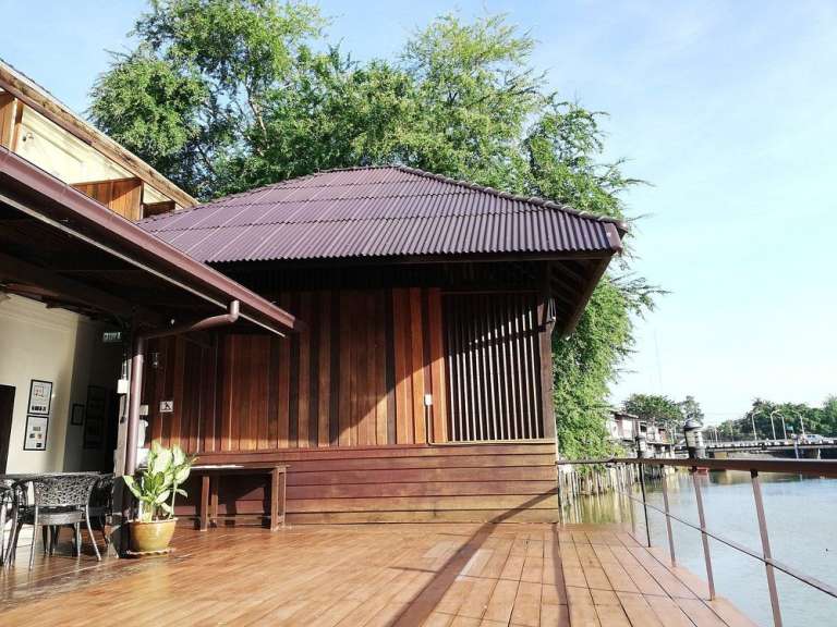 Ein Holzhaus mit einem braunen Dach steht neben einem Fluss