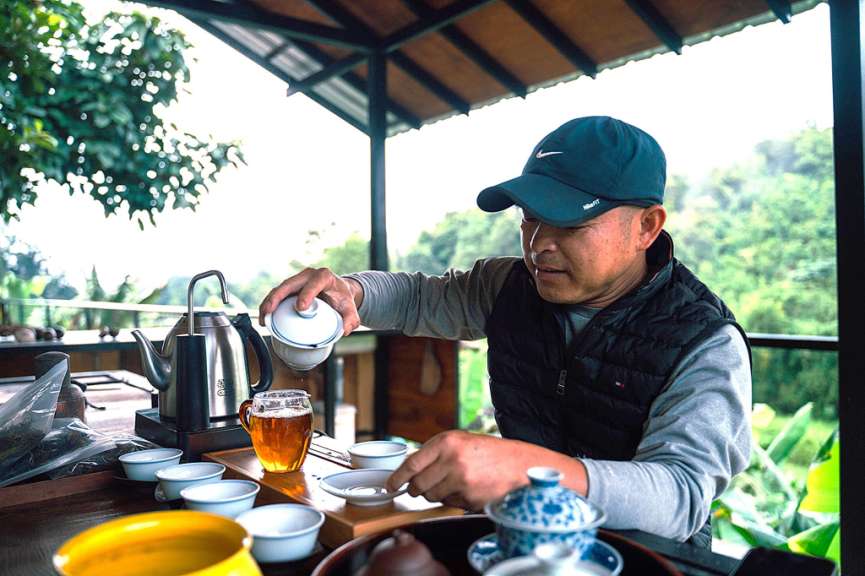 Ein Mann in einer blauen nike-Mütze gießt Tee in eine Tasse