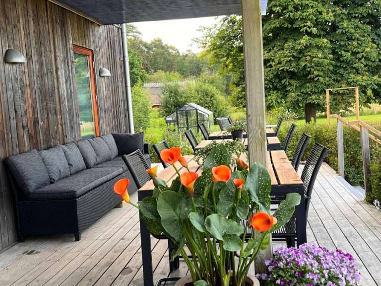 Eine Couch sitzt auf einem Deck neben einem Tisch und Stühlen