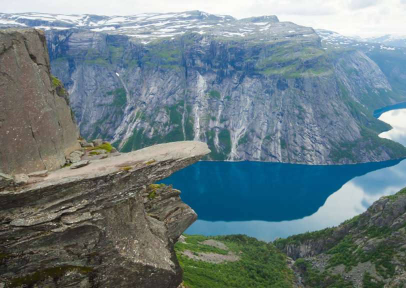 Eine Person sitzt auf einem Felsen über einem See