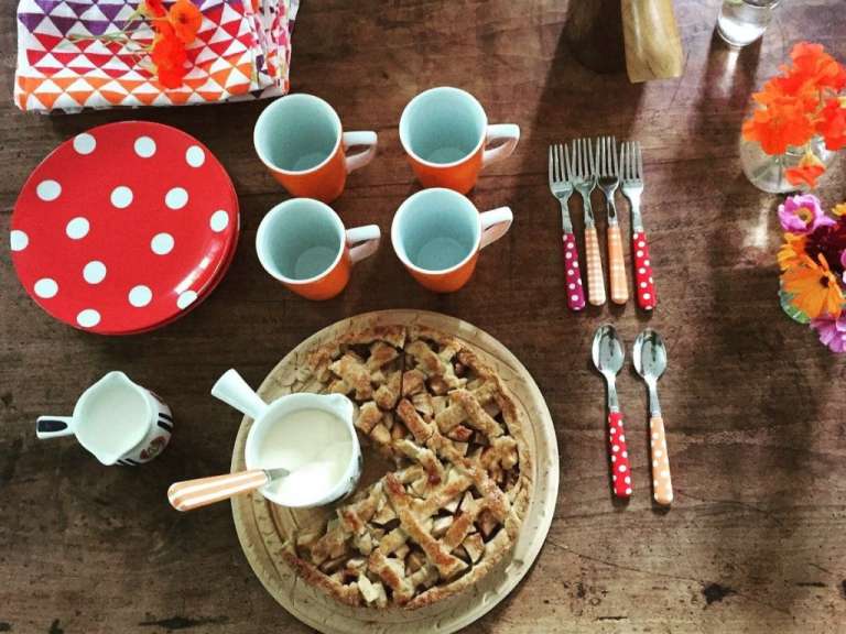 Auf einem tisch steht ein apfelkuchen mit milch und löffeln