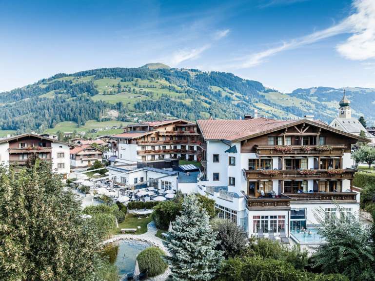 Auf diesem Bild ist ein Alpenresort mit einem Pool und einer atemberaubenden Bergkulisse zu sehen.