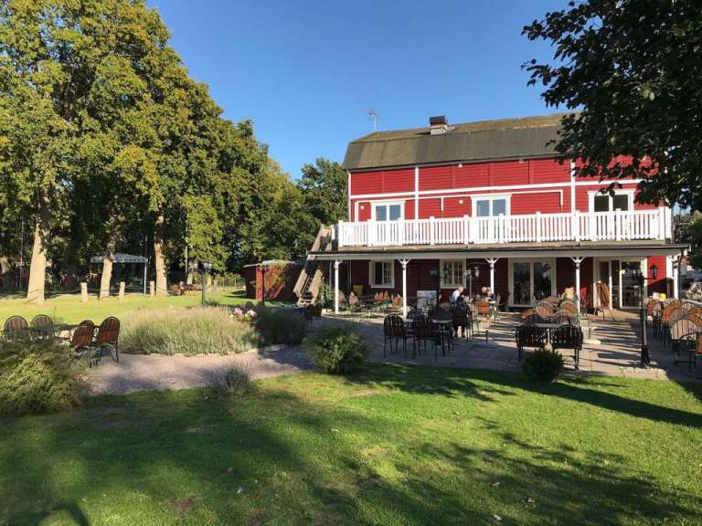 Eine rote Scheune mit einem weißen Deck und Tisch und Stühlen davor
