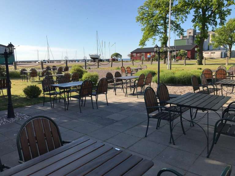 Tische und Stühle auf einer Terrasse mit einem Boot im Hintergrund